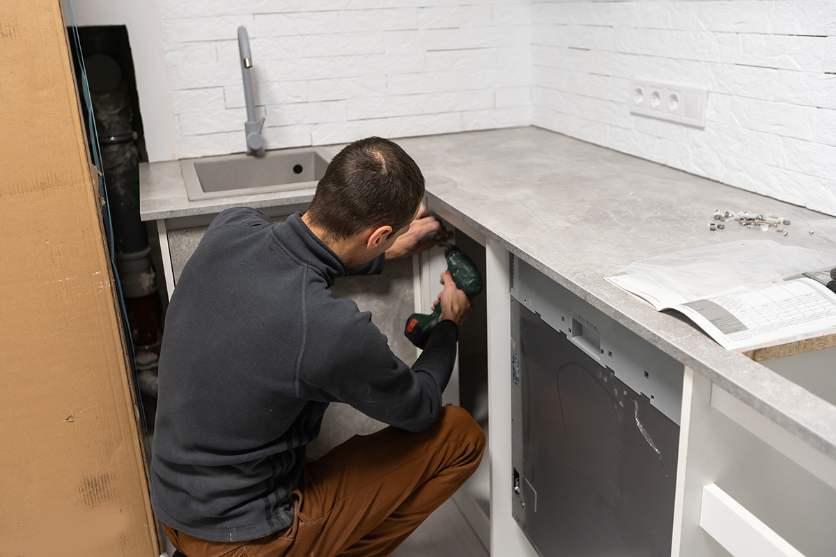 Fotografía de un hombre remodelando una cocina y haciendo un ajuste sobre la barra de la tarja