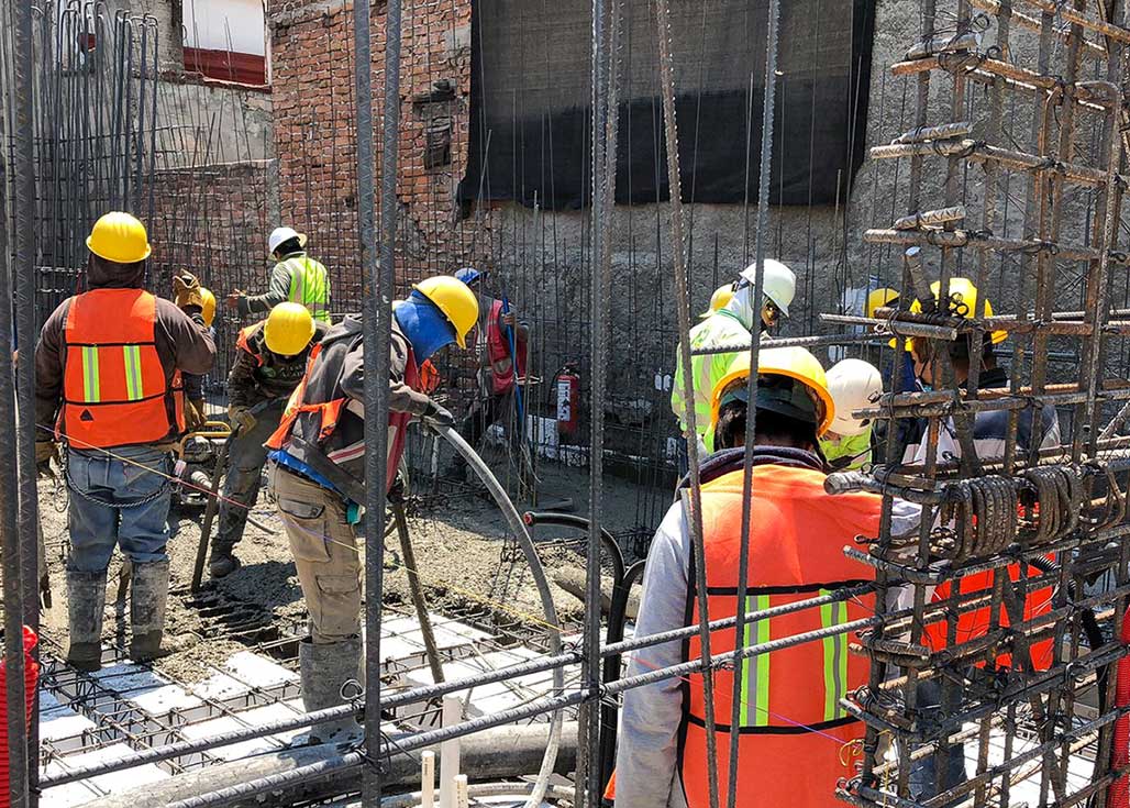 Foto de albañiles en una construcción haciendo curado de concreto