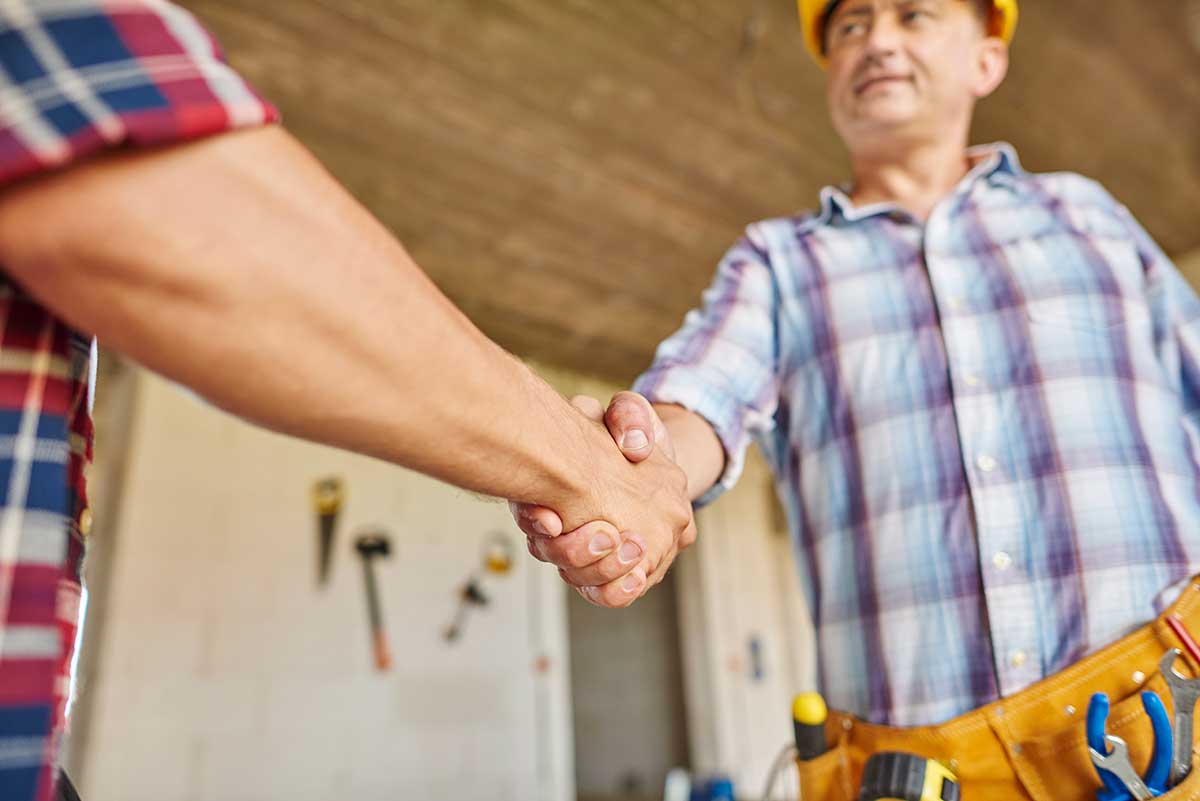 Foto de un albañil o trabajador de la construcción estrechando la mano del cliente. 